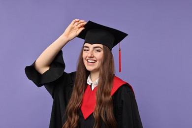 Photo of Happy student after graduation on violet background