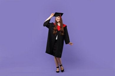 Photo of Happy student after graduation on violet background