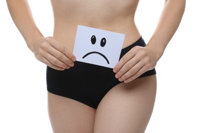 Photo of STD (sexually transmitted disease). Woman holding sticky note with drawn sad face on white background, closeup