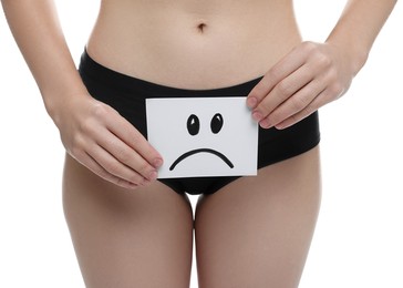 Photo of STD (sexually transmitted disease). Woman holding sticky note with drawn sad face on white background, closeup