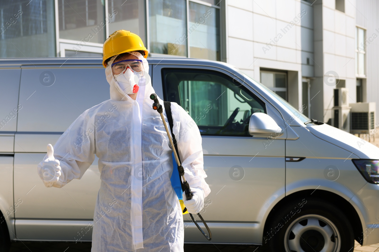 Photo of Pest control worker with spray tank showing thumbs up outdoors