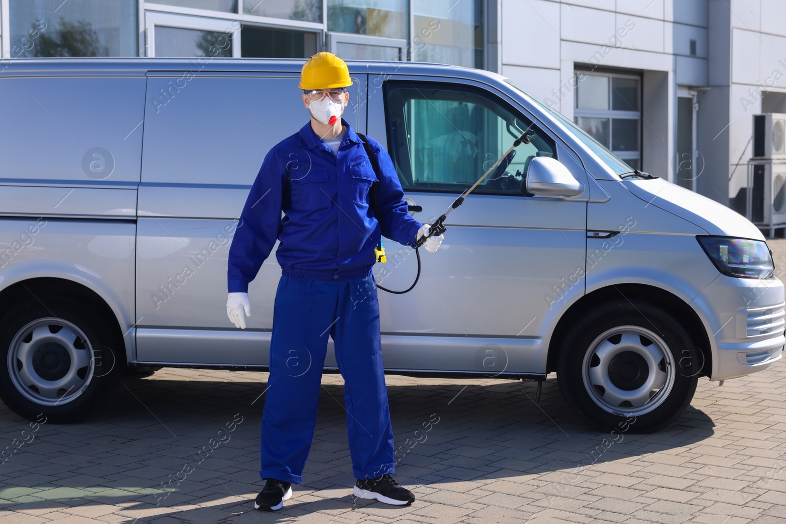 Photo of Pest control worker with spray tank outdoors