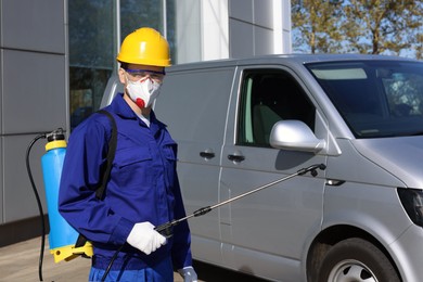 Photo of Pest control worker with spray tank near gray minibus outdoors