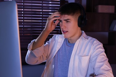 Photo of Young man playing video game at table indoors