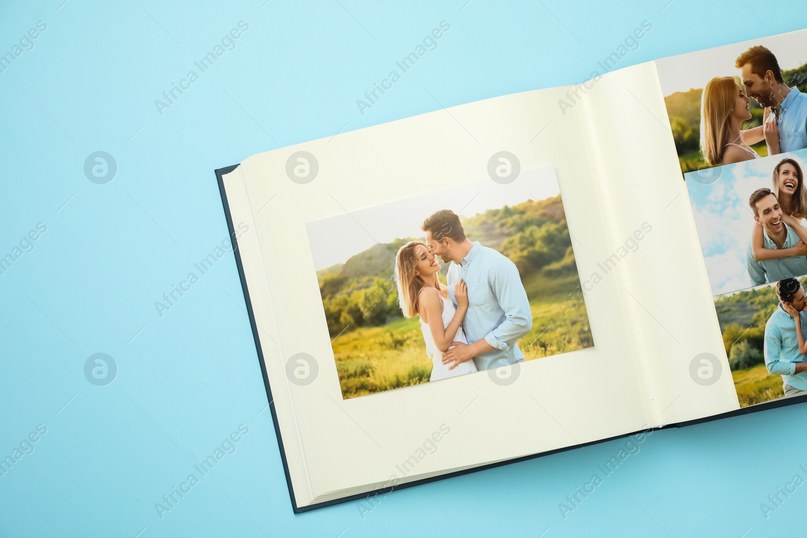 Photo of Open photo album with different photos on light blue background, top view