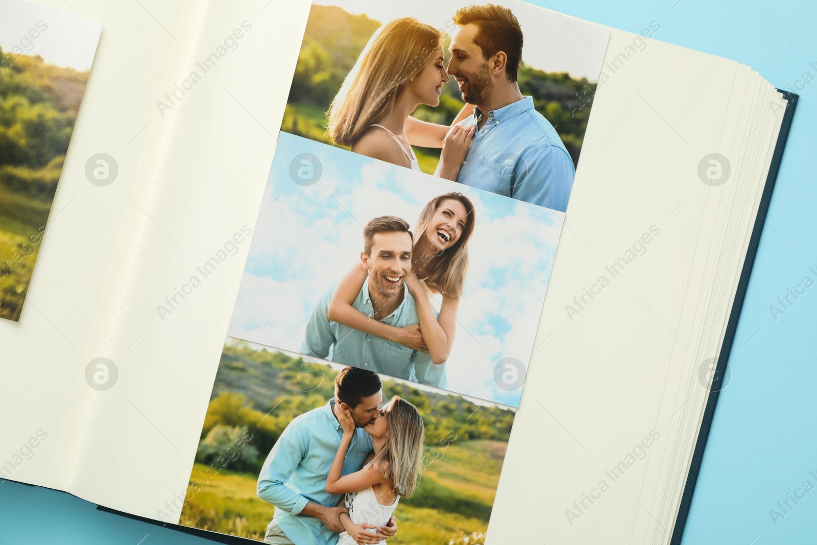 Photo of Open photo album with different photos on light blue background, top view