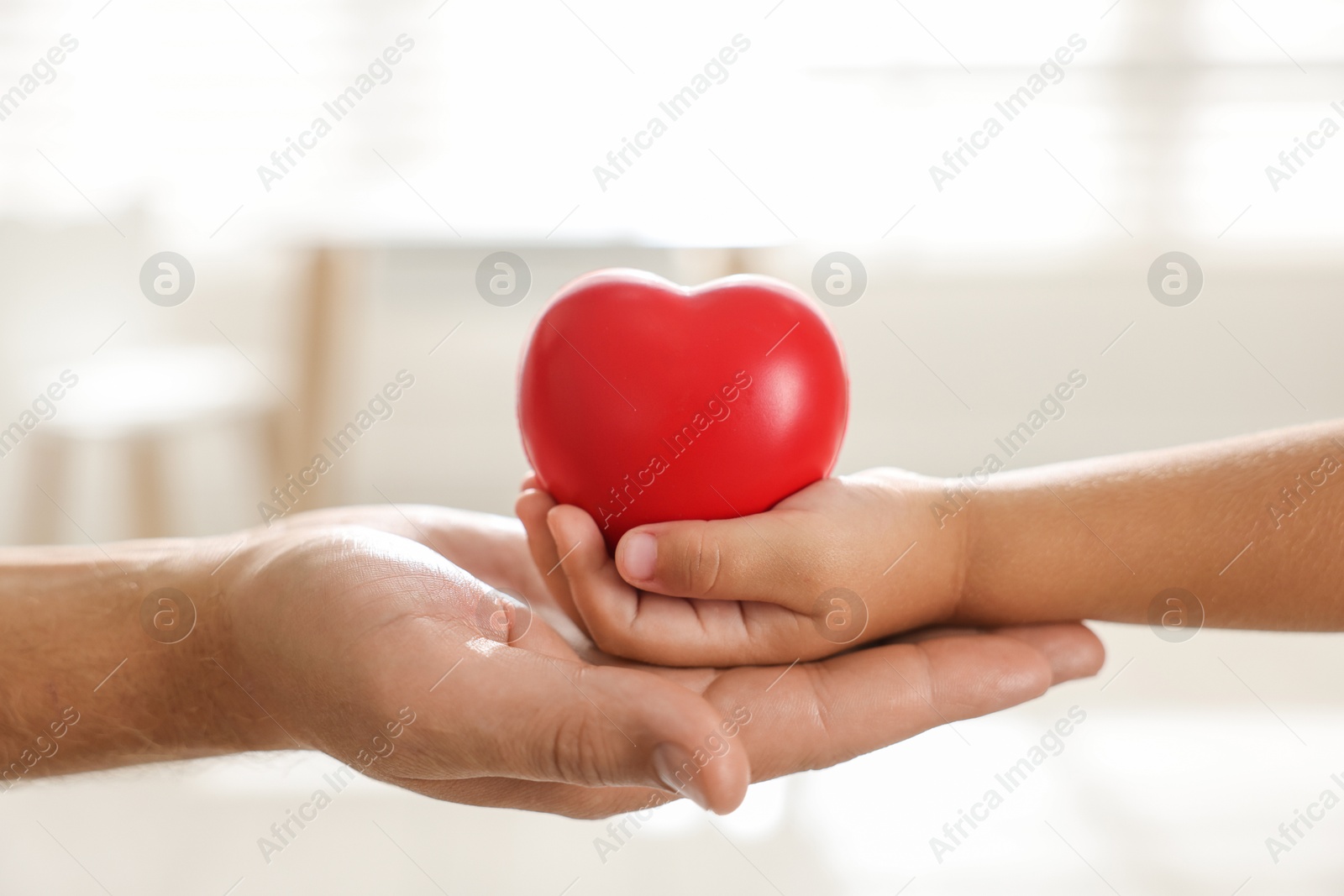 Photo of Little girl and her father with red heart figure indoors, closeup