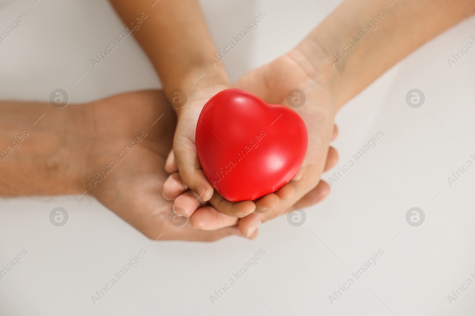 Photo of Little girl and her father with red heart figure on white background, top view