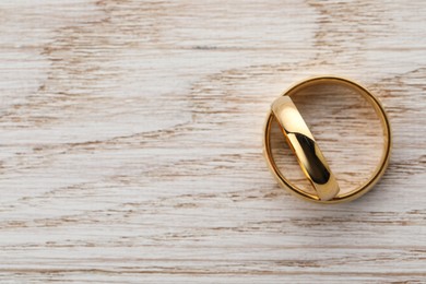 Photo of Beautiful golden wedding rings on wooden table, top view. Space for text