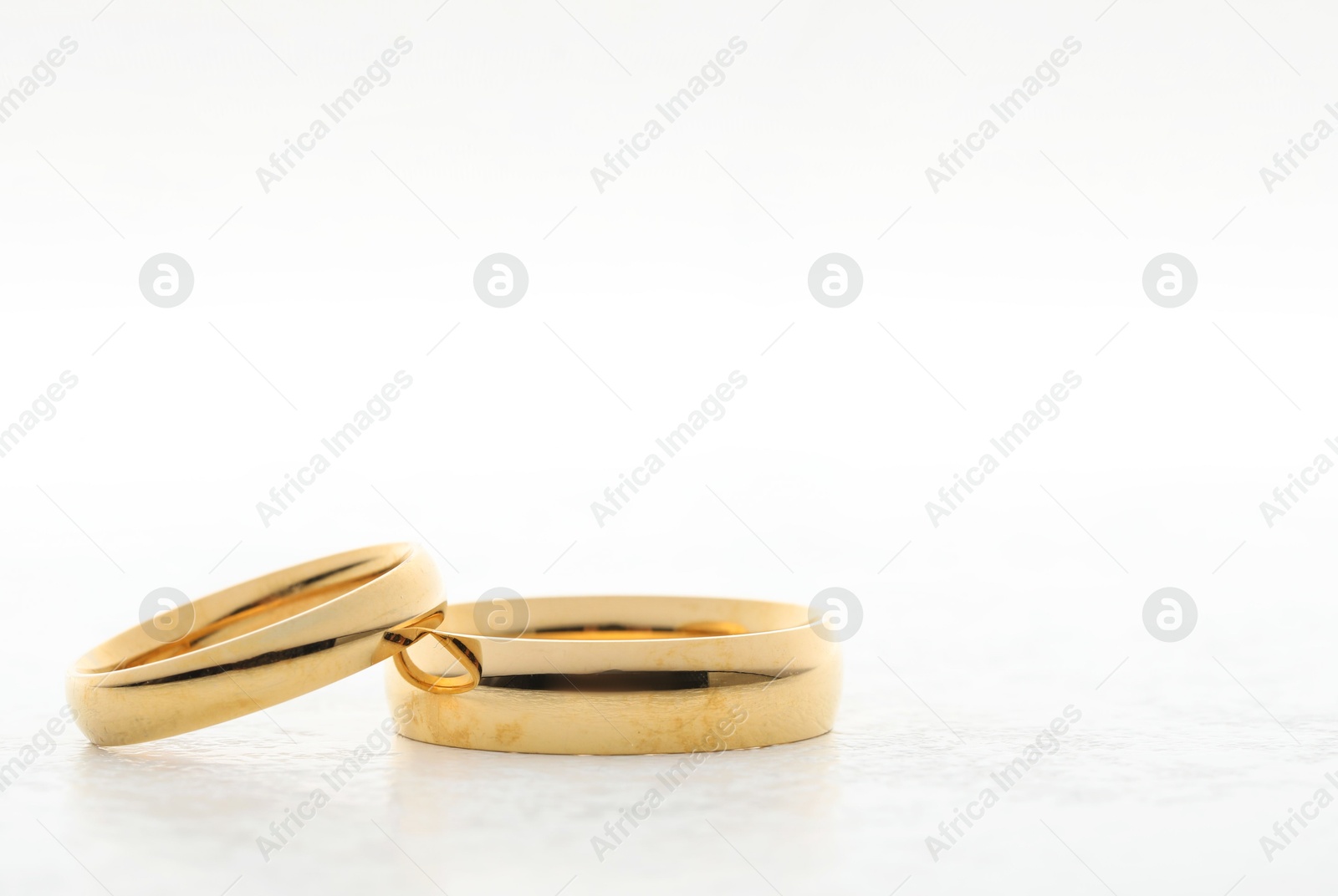 Photo of Beautiful golden wedding ring on white table, space for text