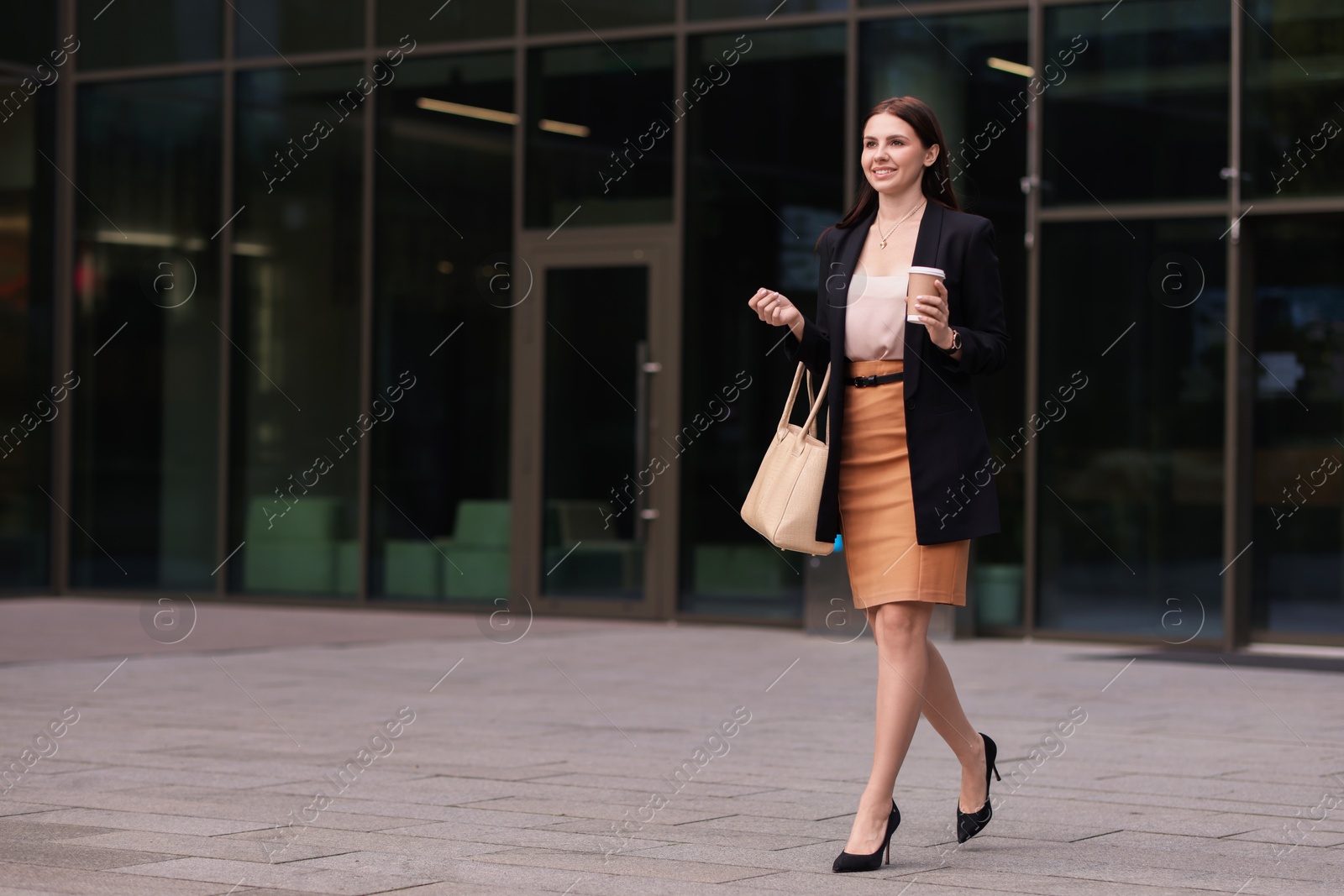 Photo of Woman in stylish formal suit with cup of coffee outdoors. Space for text