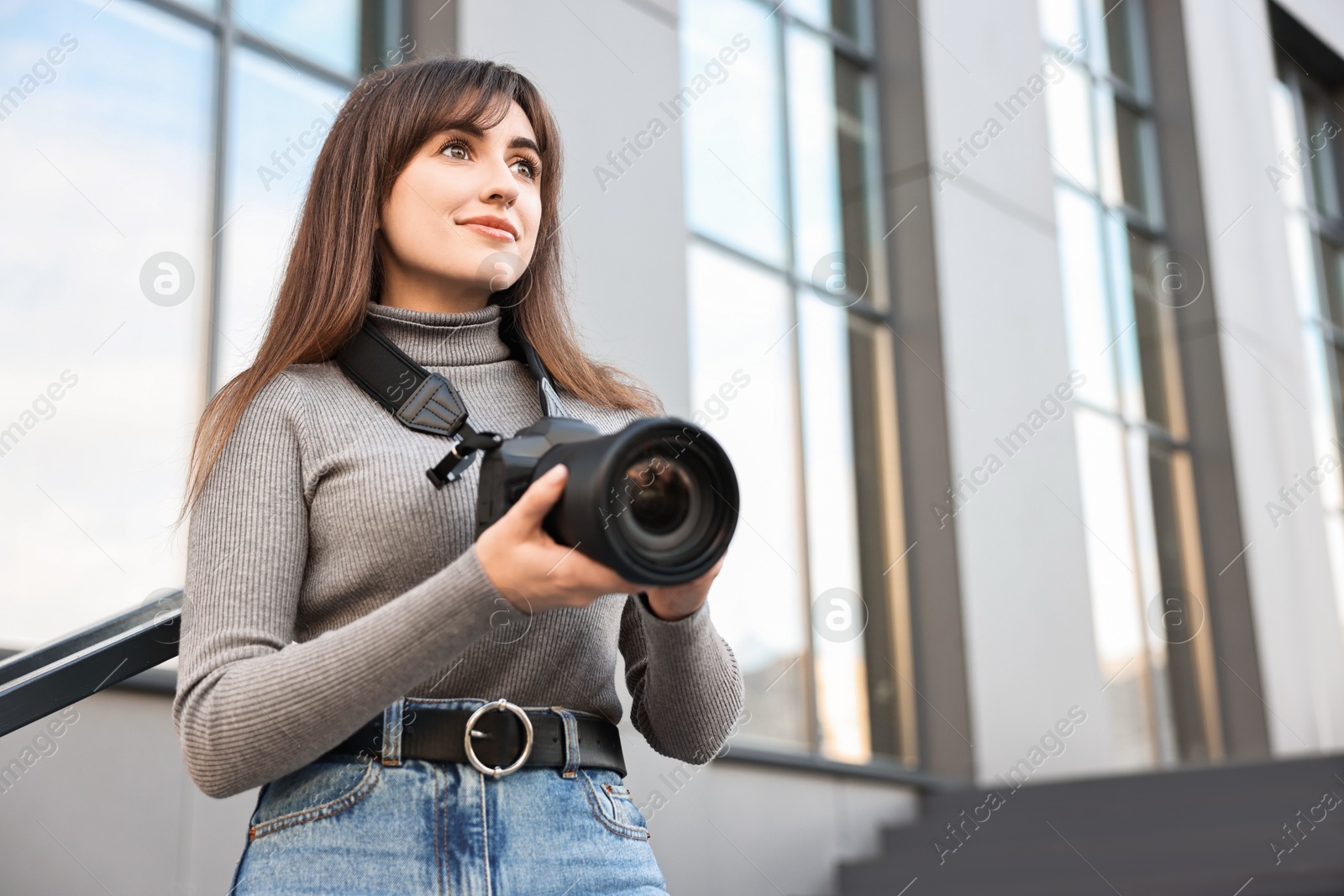 Photo of Professional photographer with digital camera outdoors, low angle view. Space for text