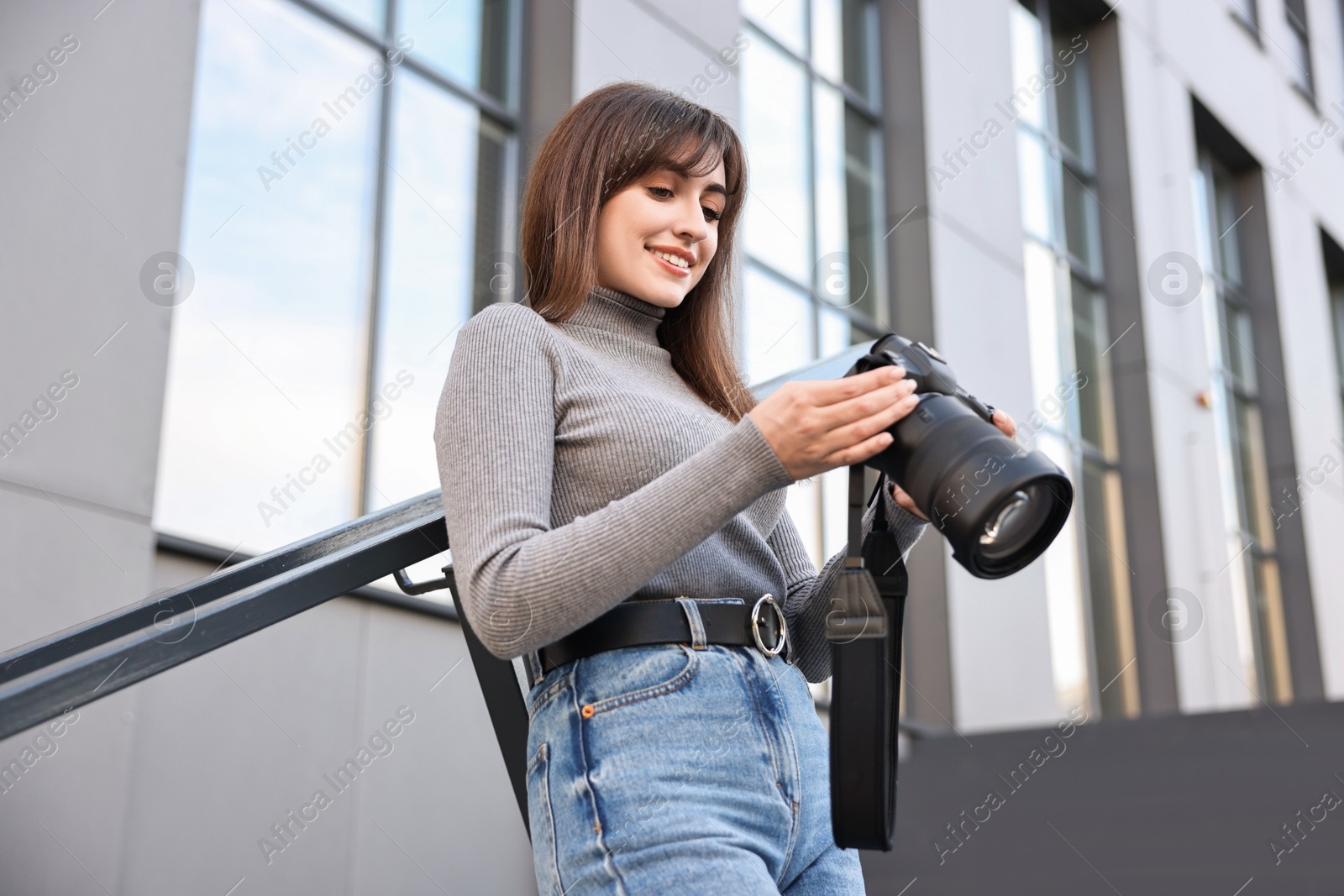 Photo of Professional photographer with digital camera outdoors, low angle view