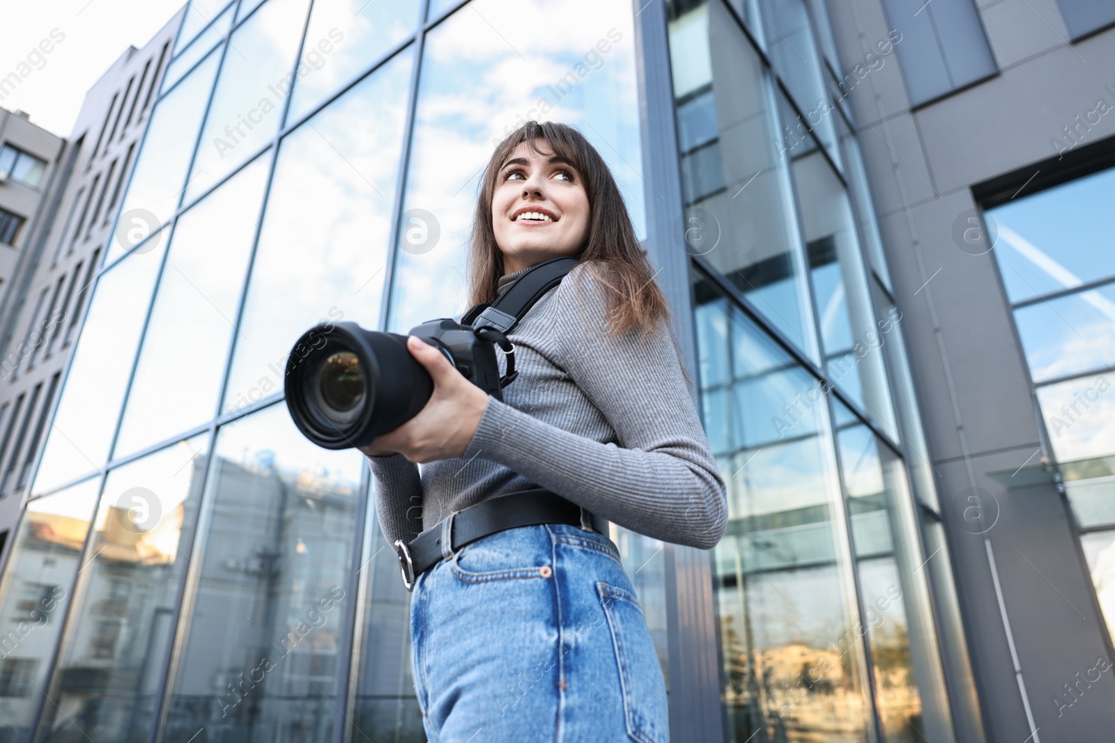 Photo of Professional photographer with digital camera outdoors, low angle view