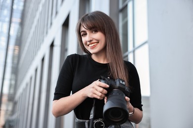 Professional photographer with digital camera near building outdoors