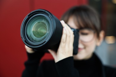 Professional photographer taking picture with camera outdoors, selective focus