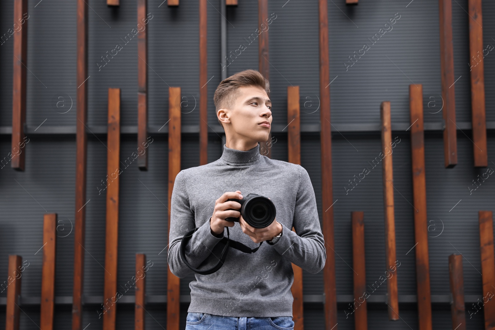 Photo of Professional photographer with modern camera near wall outdoors