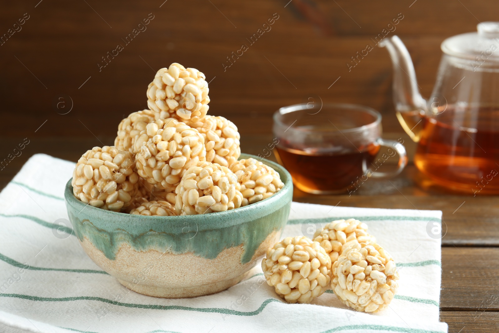 Photo of Delicious puffed rice balls in bowl and tea on wooden table, closeup