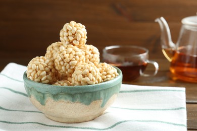 Photo of Delicious puffed rice balls in bowl and tea on wooden table, closeup