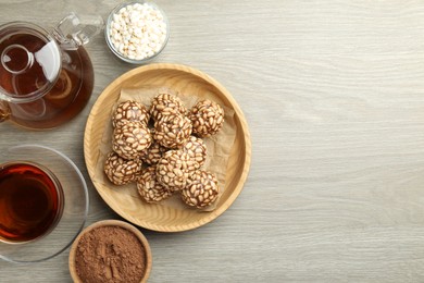 Photo of Tasty chocolate puffed rice balls served with tea on wooden table, flat lay. Space for text