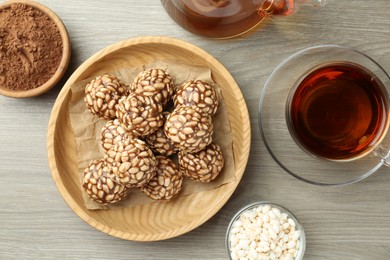 Tasty chocolate puffed rice balls served with tea on wooden table, flat lay