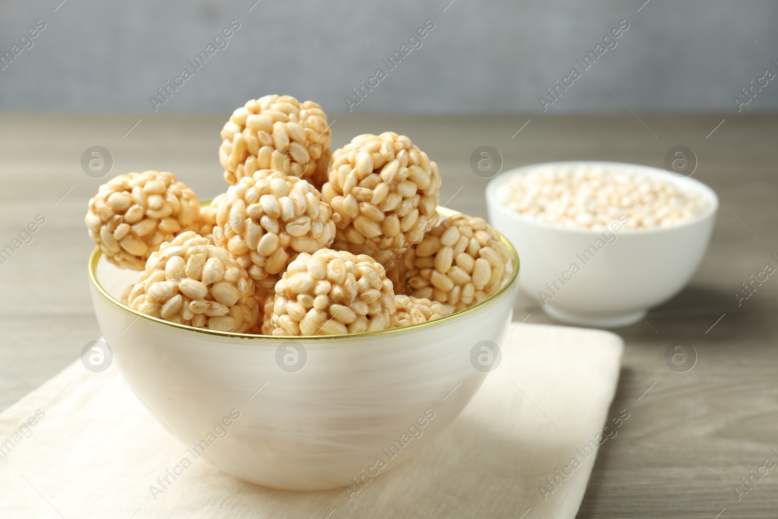 Photo of Tasty puffed rice balls in bowl on wooden table, closeup