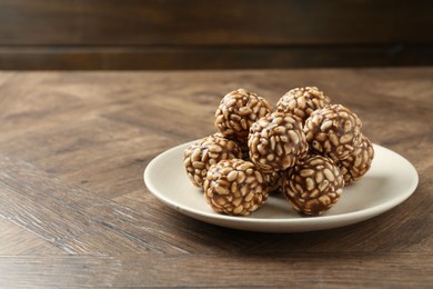 Photo of Tasty chocolate puffed rice balls on wooden table, space for text