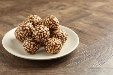 Tasty chocolate puffed rice balls on wooden table, closeup. Space for text