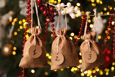 Photo of Christmas advent calendar with gifts and decor hanging on blurred background, closeup