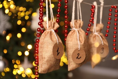 Photo of Christmas advent calendar with gifts and decor hanging indoors, closeup