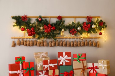 Photo of Christmas advent calendar with gifts and decor hanging on white wall indoors