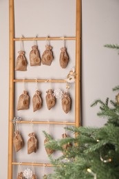 Photo of Advent calendar with gifts hanging on white wall near Christmas tree indoors