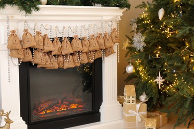 Photo of Advent calendar with gifts and decor hanging on fireplace Christmas near tree indoors