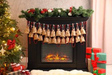 Photo of Advent calendar with gifts and decor hanging on fireplace Christmas near tree indoors