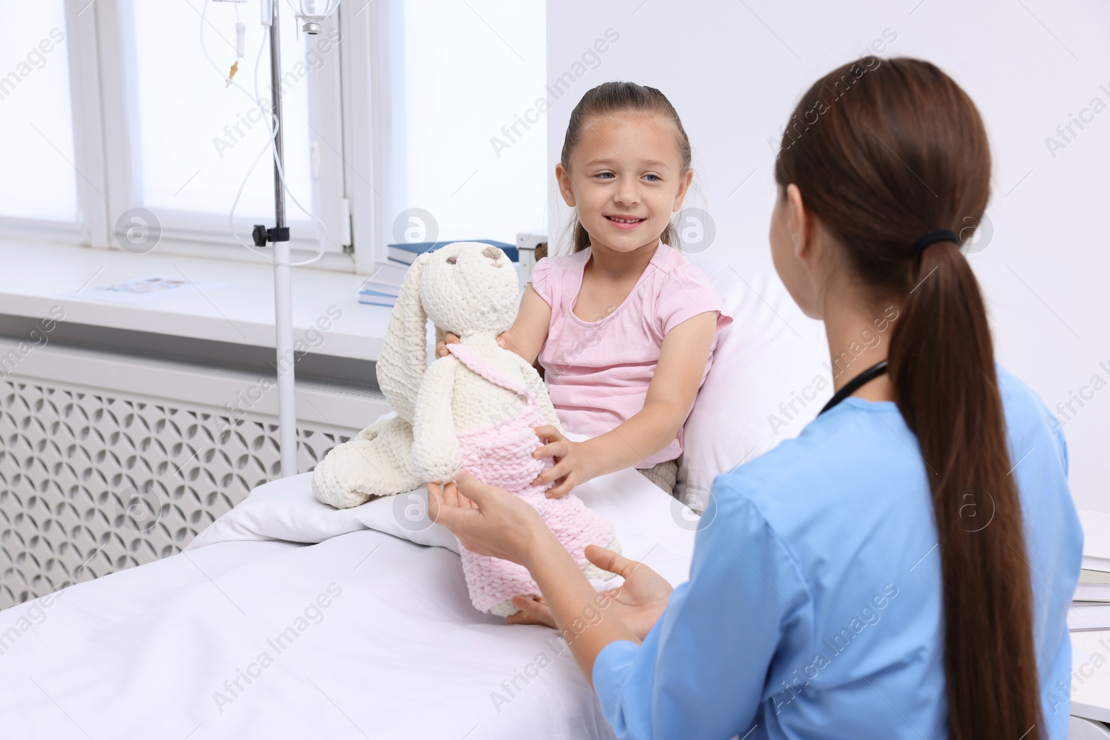 Photo of Doctor examining little girl on bed at hospital