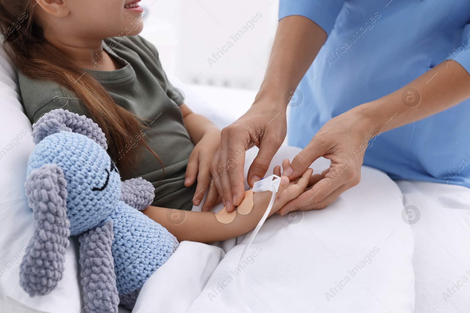 Photo of Doctor examining little girl on bed at hospital, closeup