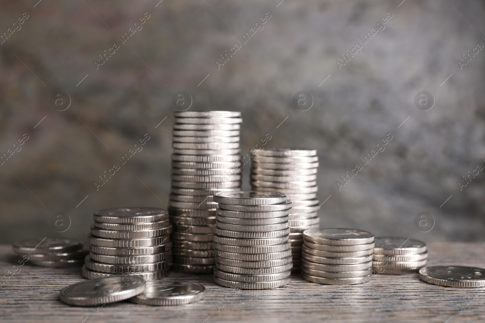 Photo of Stacked coins on wooden table against blurred grey background, closeup. Salary concept