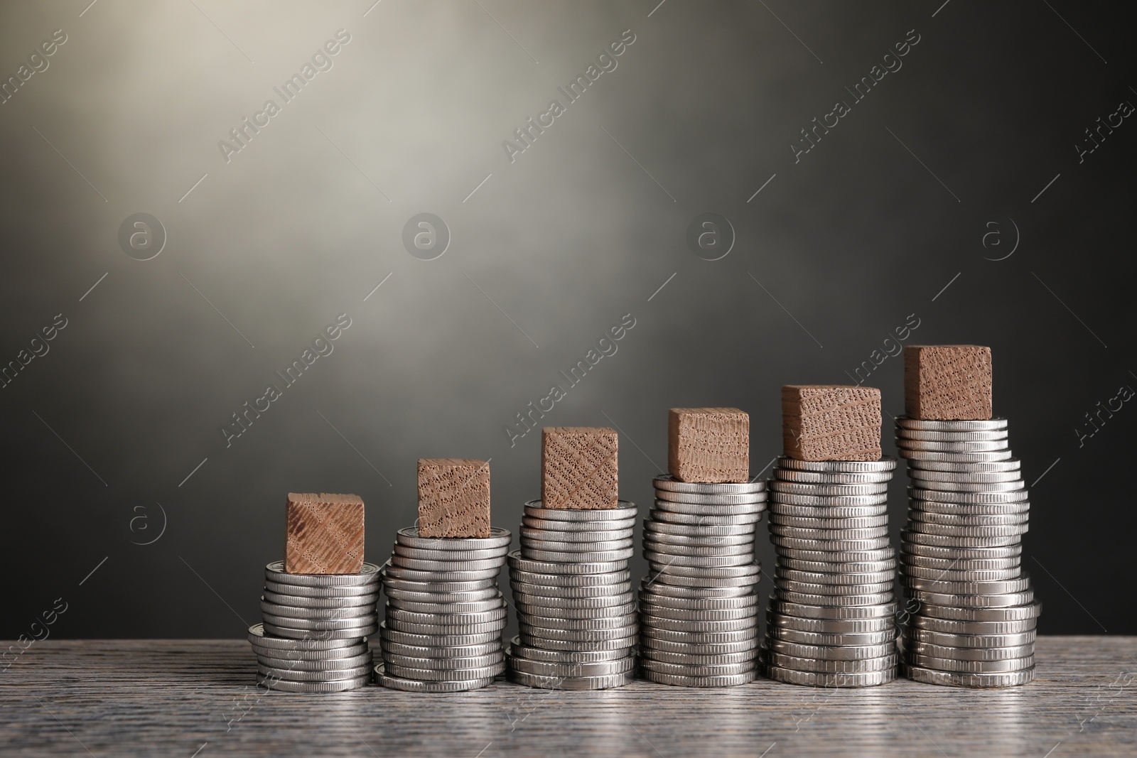 Photo of Stacked coins and blank cubes on wooden table, closeup with space for text. Salary concept