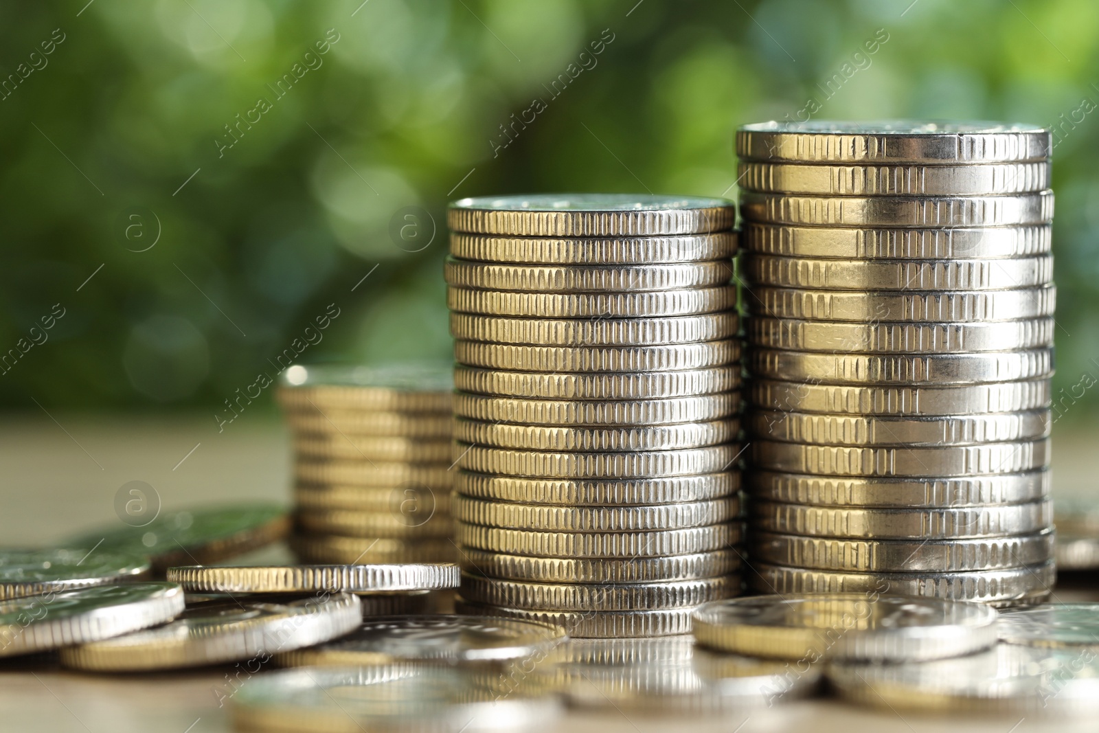 Photo of Many coins on table against blurred green background, closeup. Salary concept