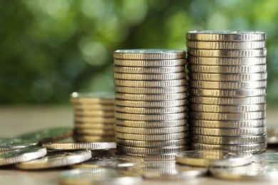 Photo of Many coins on table against blurred green background, closeup. Salary concept