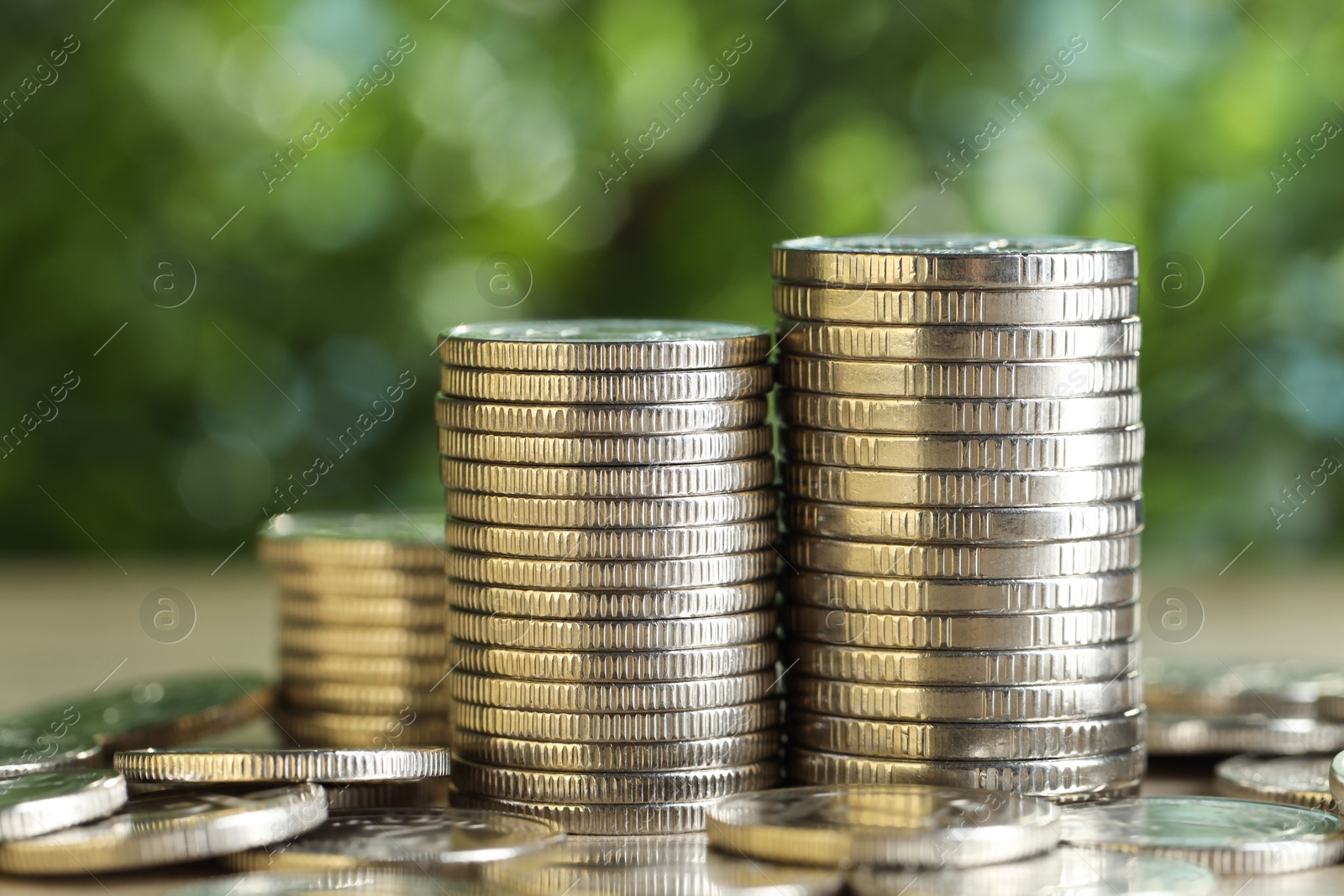 Photo of Many coins on table against blurred green background, closeup. Salary concept