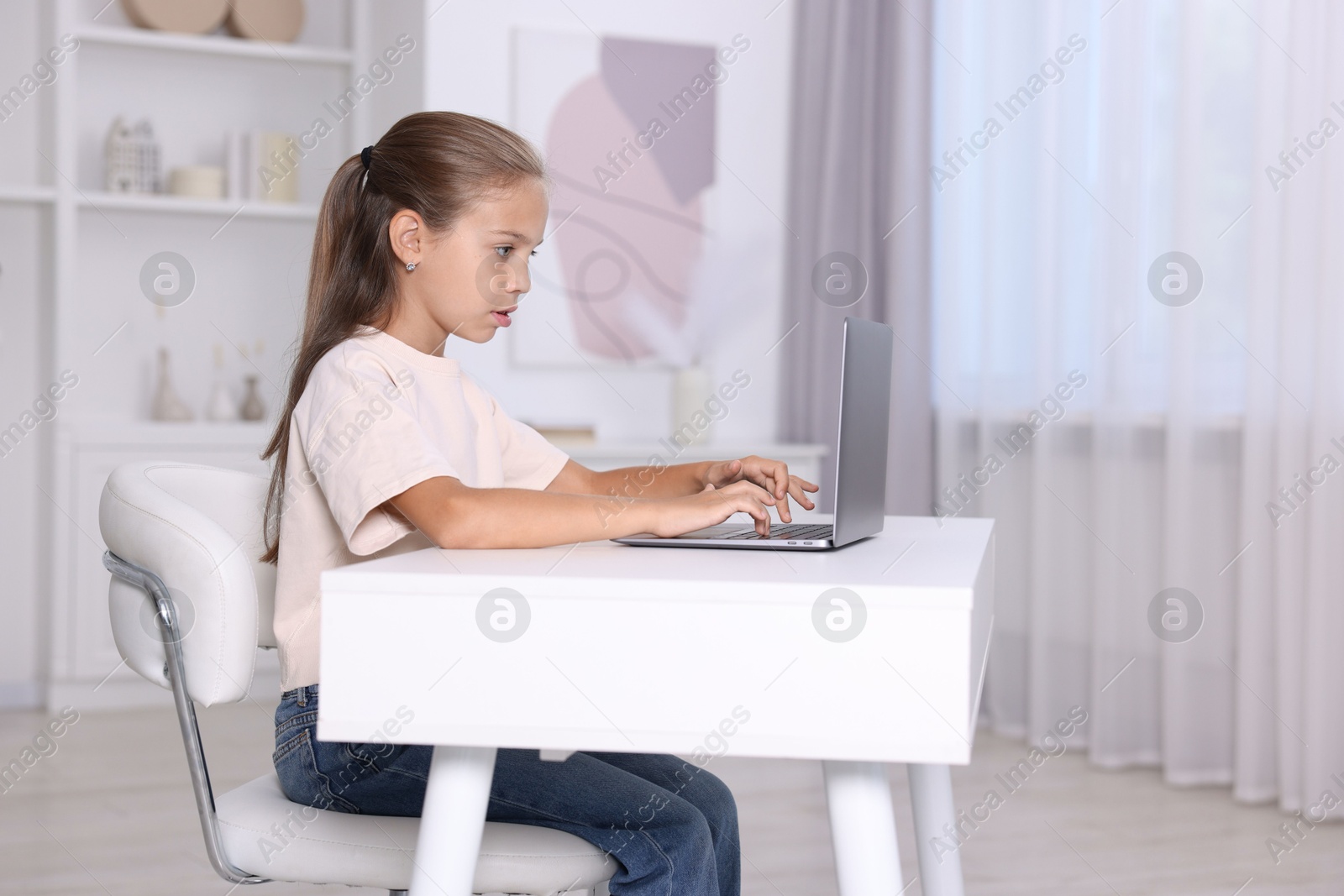 Photo of Girl with correct posture using laptop at white desk indoors