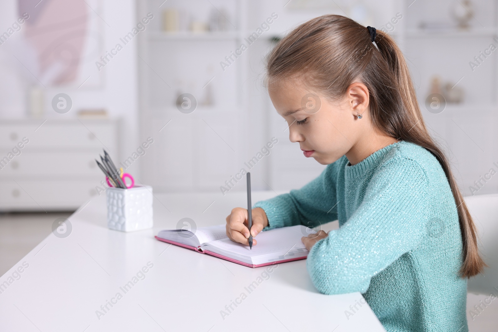 Photo of Girl with correct posture doing homework at white desk indoors