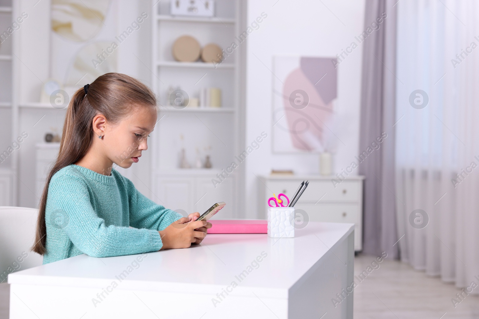 Photo of Girl with correct posture using smartphone at white desk indoors