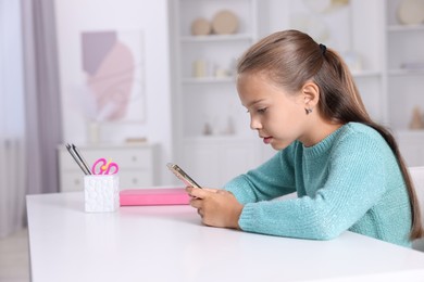 Photo of Girl with incorrect posture using smartphone at white desk indoors