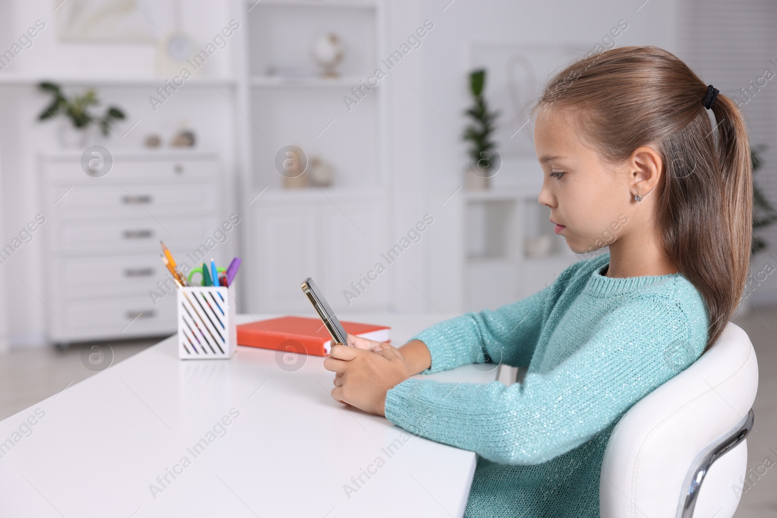 Photo of Girl with correct posture using smartphone at white desk indoors