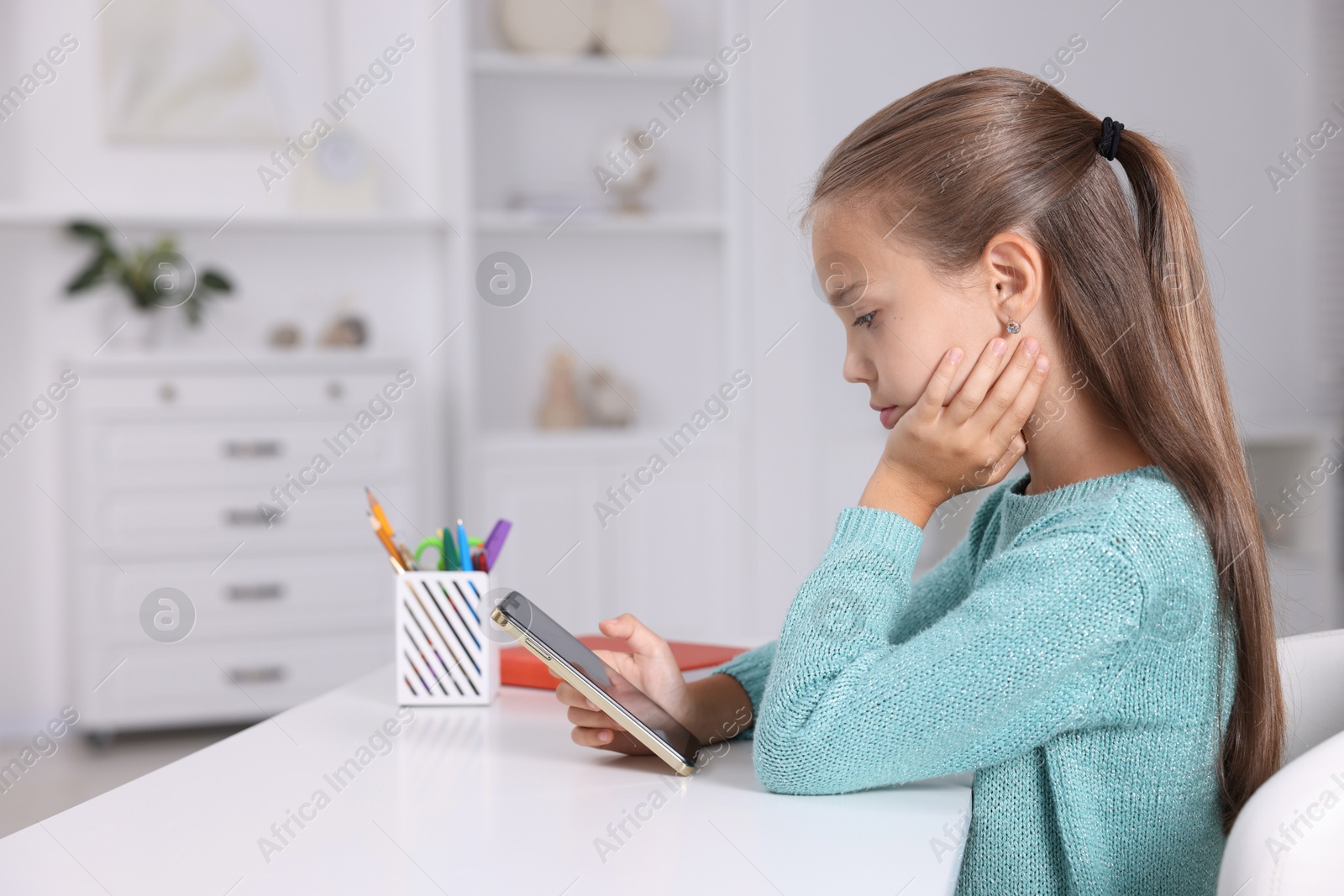 Photo of Girl with correct posture using smartphone at white desk indoors