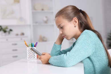 Girl with incorrect posture using smartphone at white desk indoors