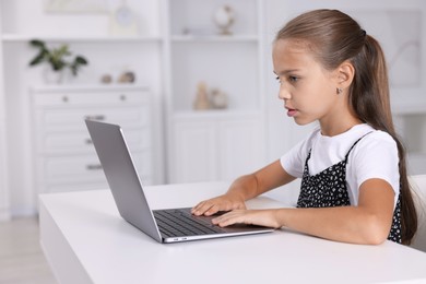 Photo of Girl with correct posture using laptop at white desk indoors