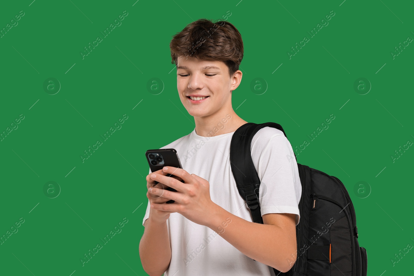 Photo of Teenage boy with smartphone and backpack on green background